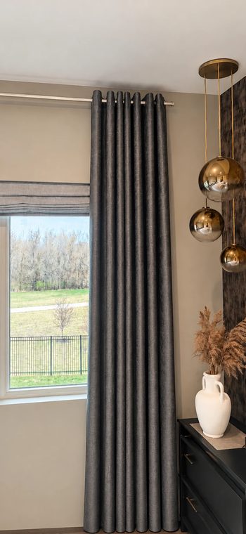 Dark floor-length curtain by a tall window