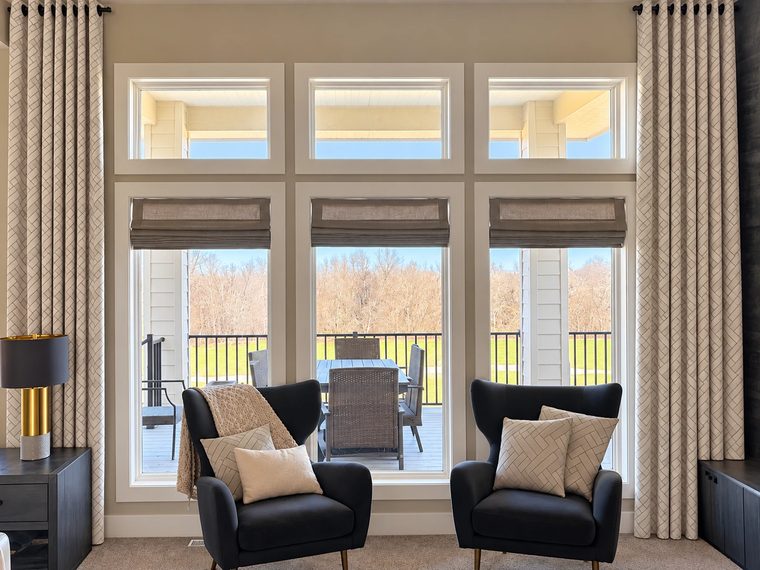 Curtains and Roman shades on a wall of windows with two armchairs